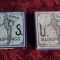 Lot 069 - Pair Of Uncle Sam Watch Main Springs Boxes With Contents