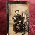 Lot 106 - Tintype - Man Sitting In Chair, Leaning On Elbow, In Hat, With Branch Gate Behind Him