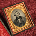 Lot 036 - Antique 1/9th Plate Ruby Ambrotype Photograph With Patriotic, Civil War Brass Mat With Eagle Carrying Flag, Drum, Canon, Rifle, Sword, Photo Of Man With Bowtie, Full Split Case