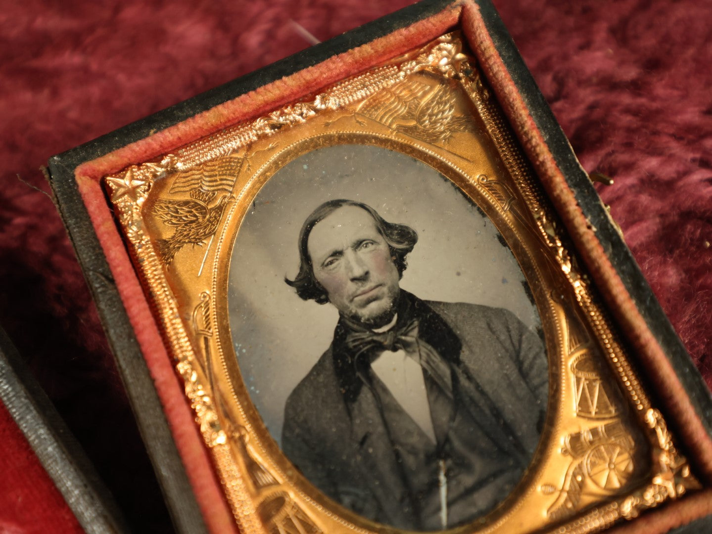 Lot 036 - Antique 1/9th Plate Ruby Ambrotype Photograph With Patriotic, Civil War Brass Mat With Eagle Carrying Flag, Drum, Canon, Rifle, Sword, Photo Of Man With Bowtie, Full Split Case
