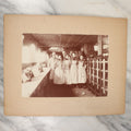 Lot 025 - Antique Boarded Occupational Photograph Of Four Women And Two Men Working In A Boot And Shoe Factory, Many Shoes Visible In Photo