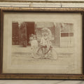 Lot 045 - Antique Framed Photo Of A Young Boy And Man, Likely His Father, With A Bike Covered In Flowers, Flower Moon, Boy In Naval Outfit, Likely For Parade, With Ice Cream Shop In Background
