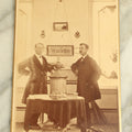 Lot 083 - Antique Interior Cabinet Card Photograph Of Two Men Standing In Front Of A Punchwork Embroidery, Taxidermy Deer Head, And More, Crosby, Photographer, Lewiston, Maine