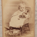 Lot 067 - Antique Cabinet Card Photograph Of A Young Baby Toddler Holding Her Doll, Seated In Chair, Harris & Greene Photographers, Utica, New York