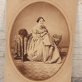 Lot 069 - Antique Matted Occupational Photograph Of An Adult Woman Seamstress, Pictured With Sewing Stand, And Scraggly Little Black Dog On Table To The Left, C.L. Obst Photographer, Pittsfield, Illinois