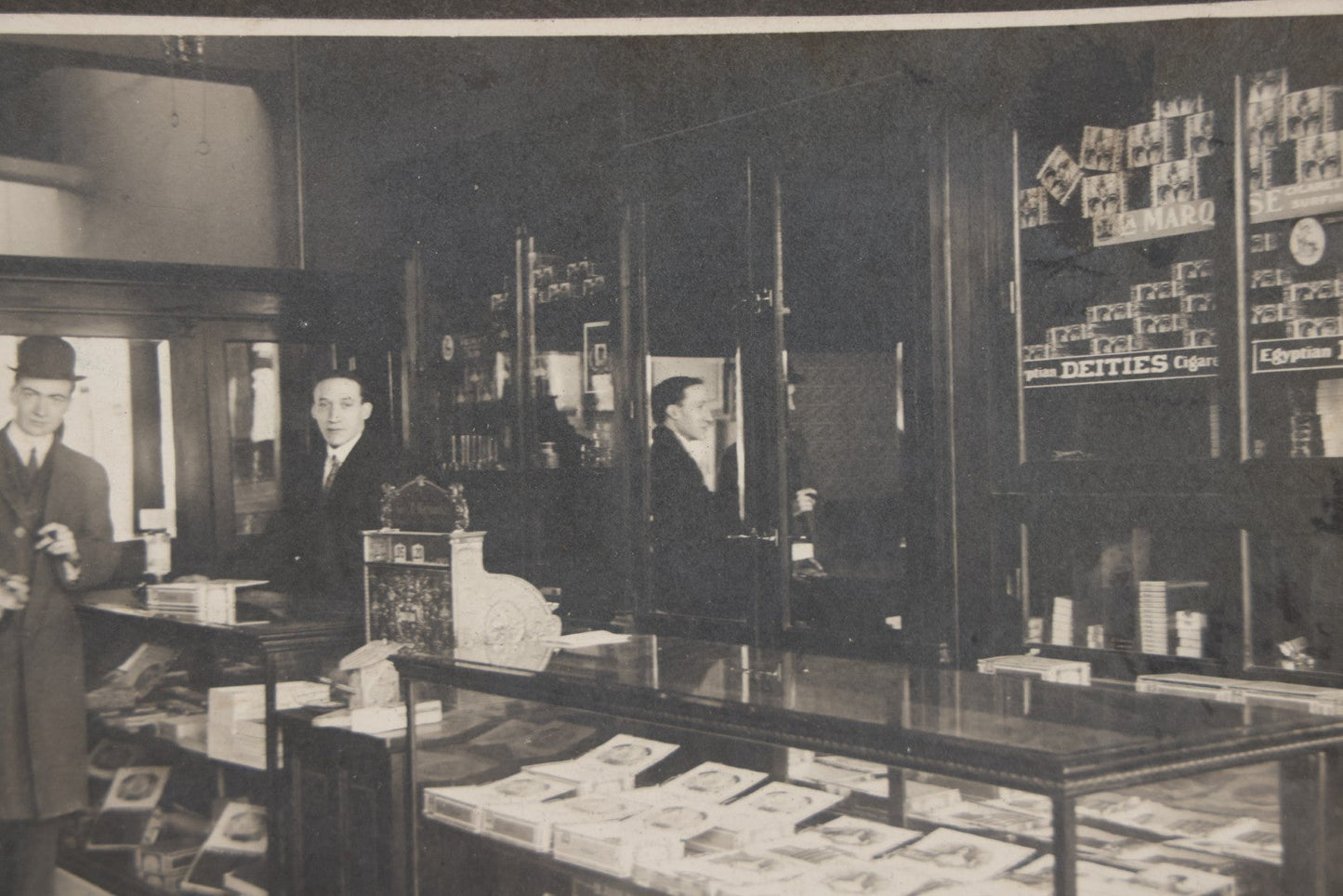Lot 109 - Antique Boarded Photo Of A Tobacco, Cigar Shop, With Man Behind Counter, Customers In Bowler Hats, Various Cigar Brands