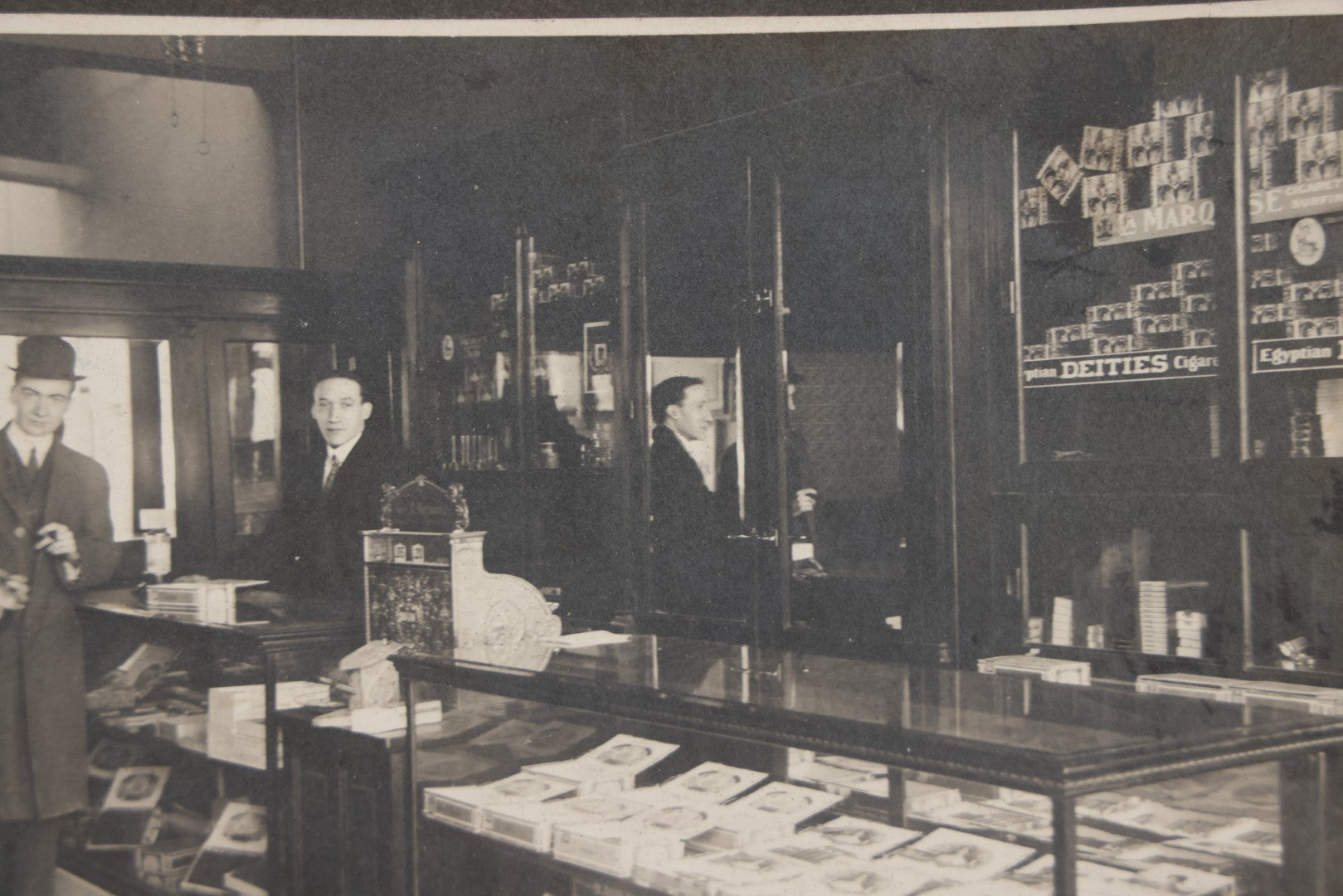 Lot 109 - Antique Boarded Photo Of A Tobacco, Cigar Shop, With Man Behind Counter, Customers In Bowler Hats, Various Cigar Brands
