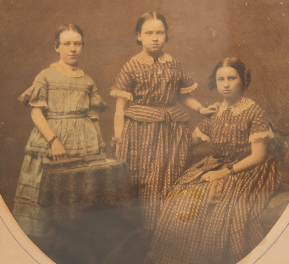 Lot 078 - Antique Framed Hand Tinted Photograph Of Three Young Girls, Likely Sisters, In Dresses, I.D. In Pencil On Verso
