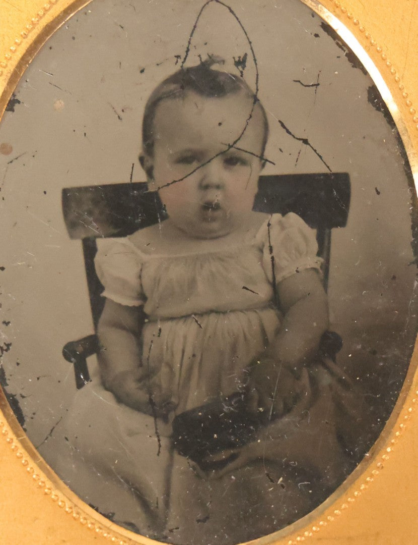 Lot 086 - Antique 1/9th Plate Ruby Ambrotype Photograph Of A Baby In A White Dress Seated In A Chair, Slack Jawed Expression, Note Scratches