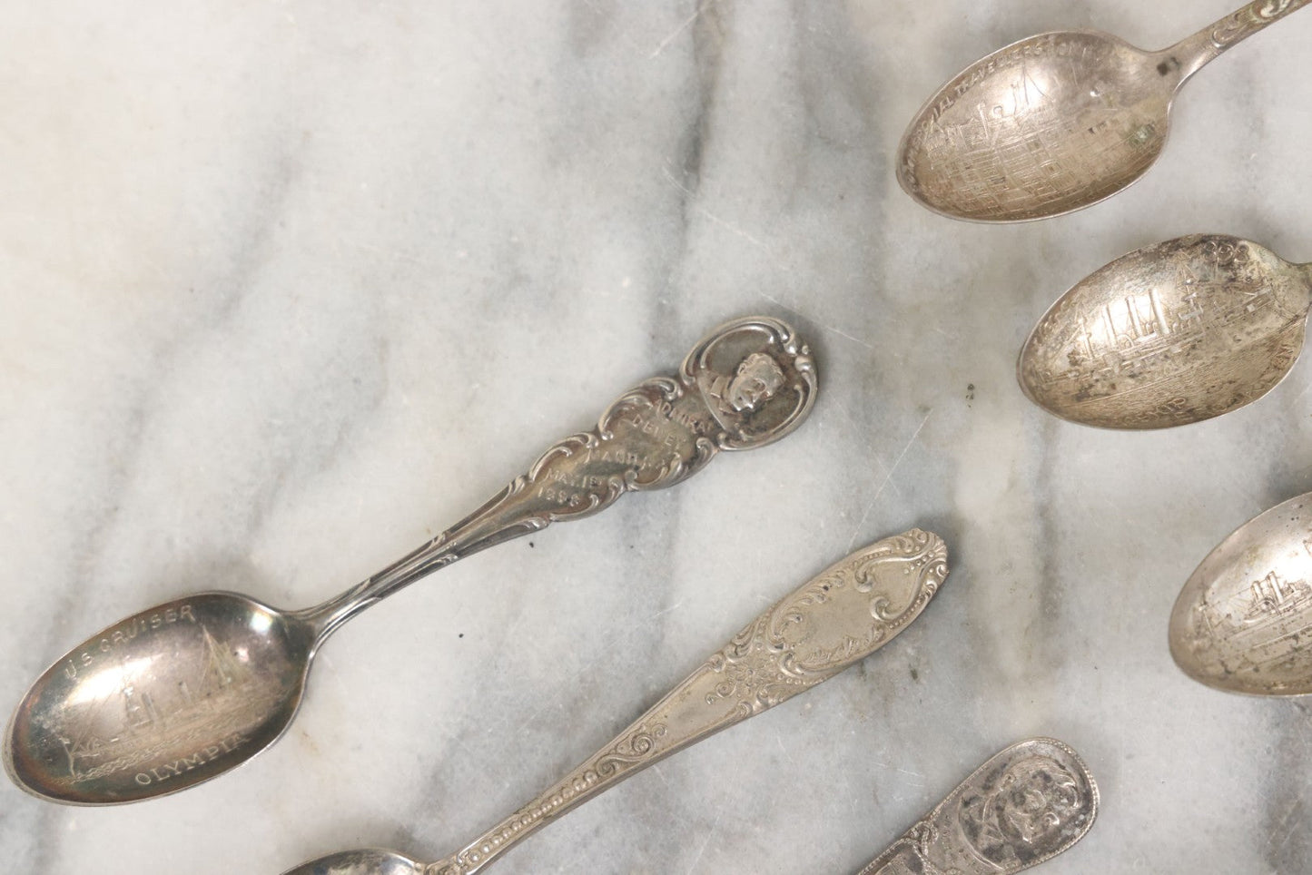 Lot 122 - Grouping Of 8 Antique Souvenir Spoons Relating To Ships And Leaders Of The Spanish American War Including The U.S. Battleship Maine, The Flagship New York, And Others, Manufactured By George E. Homer, Boston