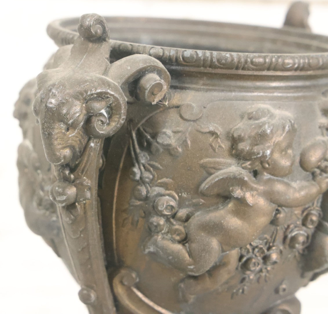Lot 010 - Antique Ornate Cast Pot Metal Urn With Cherub And Goat Head Motifs, With Makers Mark On Bottom, Marked No. 1409, 9-1/2" High