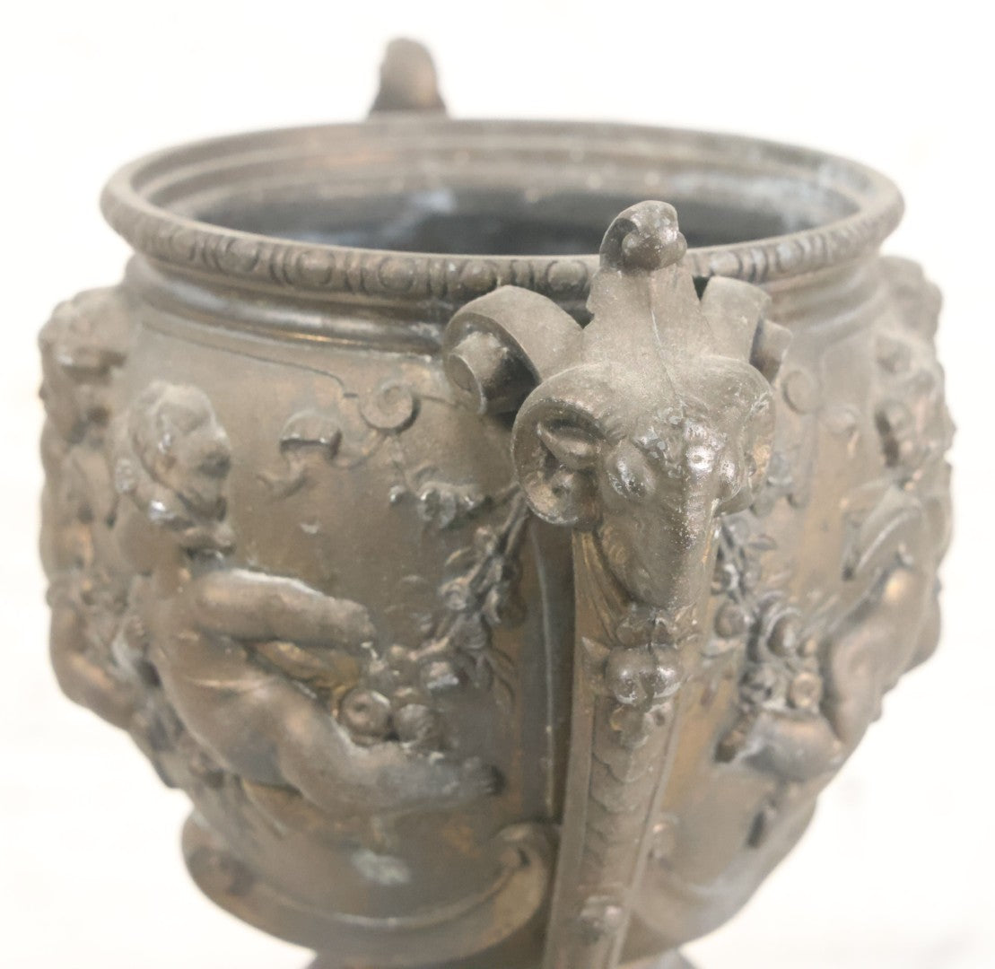 Lot 010 - Antique Ornate Cast Pot Metal Urn With Cherub And Goat Head Motifs, With Makers Mark On Bottom, Marked No. 1409, 9-1/2" High