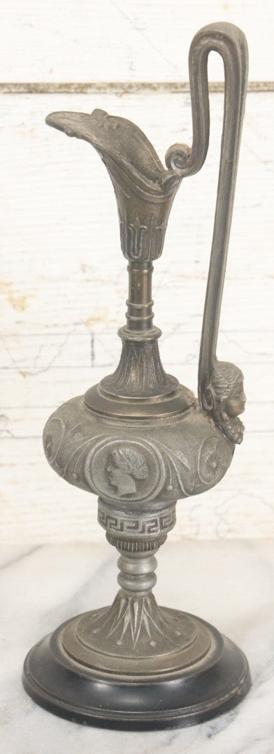 Lot 011 - Pair Of Antique Ornate Cast Pot Metal Ewers, With Woman's Head On Handle, And Woman's Head In Profile, Greek Key Design, Note Crack In Handle And Crack On Base Of One, 10-5/8" High Each