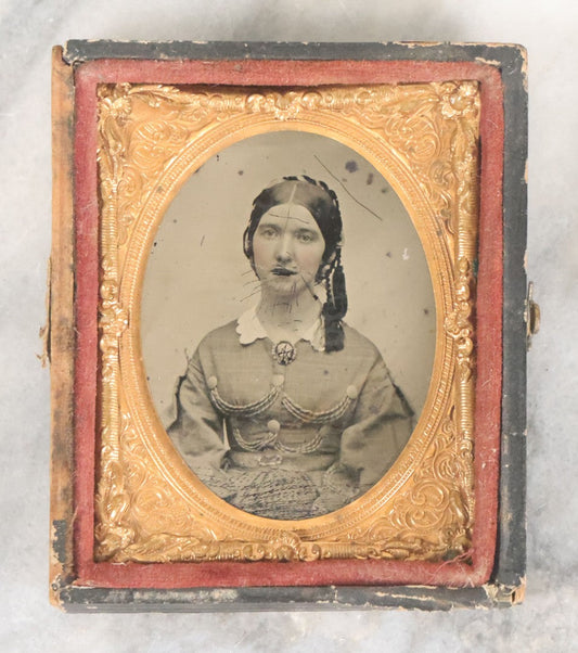 Lot 061 - Antique 1/9th Plate Ambrotype Photograph Of Young Woman, Appears To Have Been Defaced To Give Her A Beard And Other Comic Embellishments, Poor Condition, In Split Half Leatherette Union Case