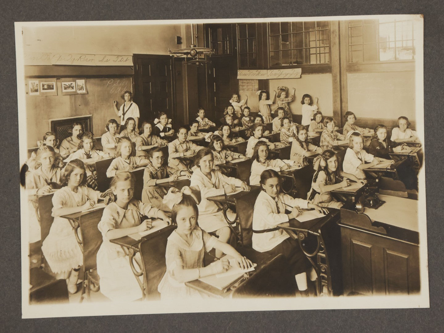 Lot 067 - Antique Boarded Interior Schoolroom Photograph Of Class Of Girls And Their Teacher (6th Grade), April 29, 1921, Partial Identification On Verso