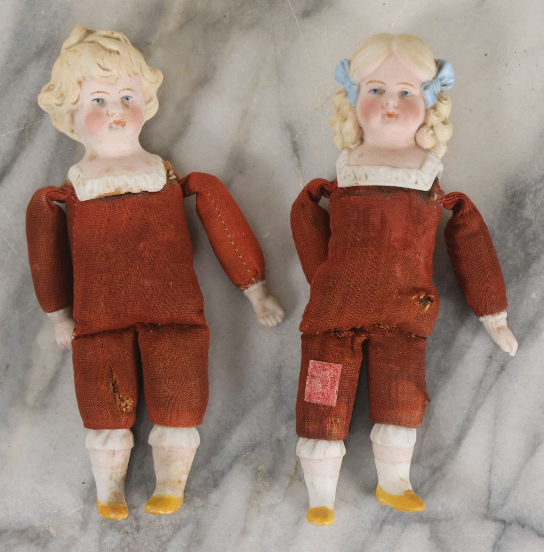 Lot 097 - Pair Of Antique Bisque Dolls With Boy And Girl With Blue Bows And Sawdust Filled Cloth Bodies, Note Girl's Head Detached, Holes In Bodies, With Sawdust Leakage, 6-1/4" Height Each
