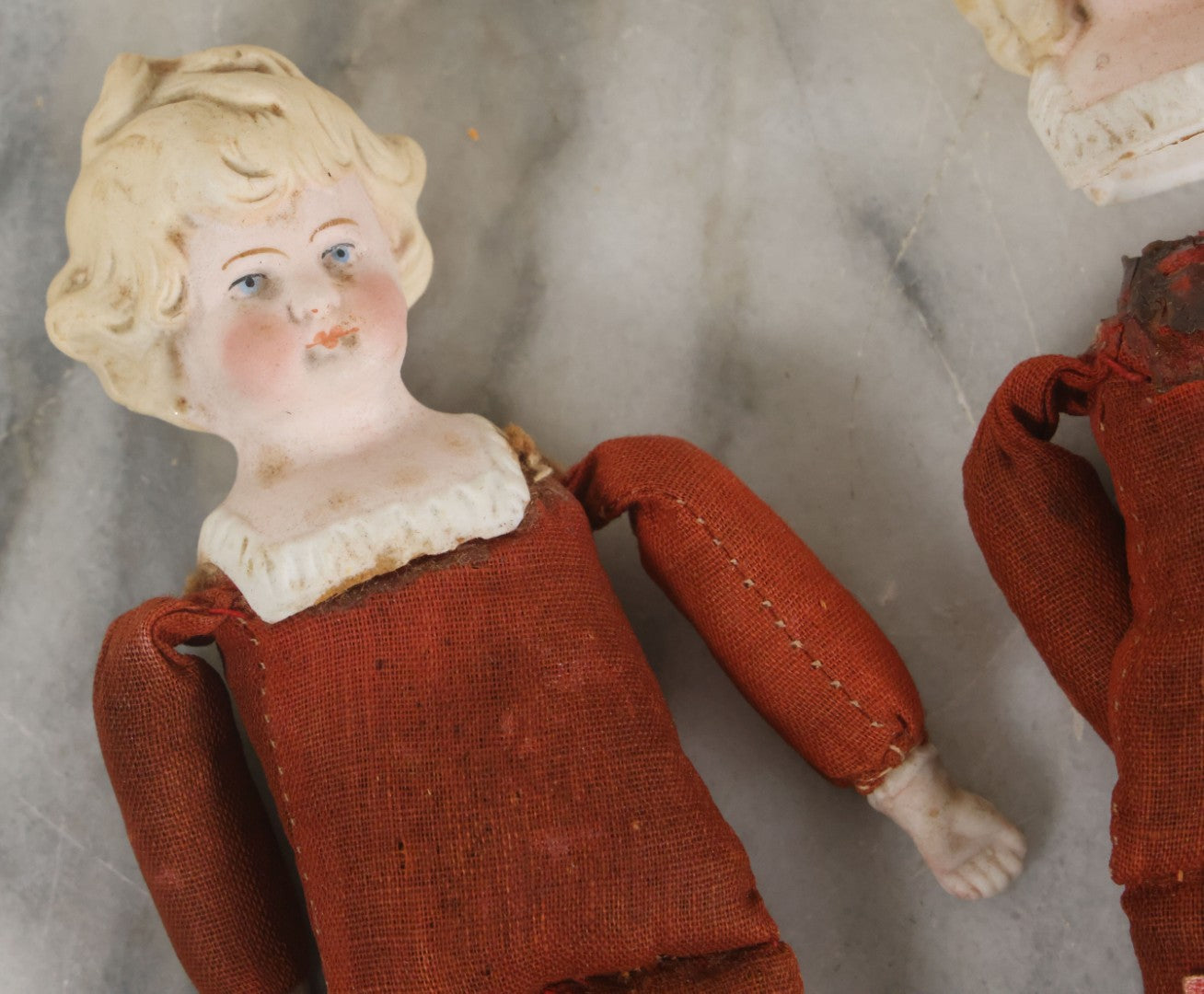Lot 097 - Pair Of Antique Bisque Dolls With Boy And Girl With Blue Bows And Sawdust Filled Cloth Bodies, Note Girl's Head Detached, Holes In Bodies, With Sawdust Leakage, 6-1/4" Height Each