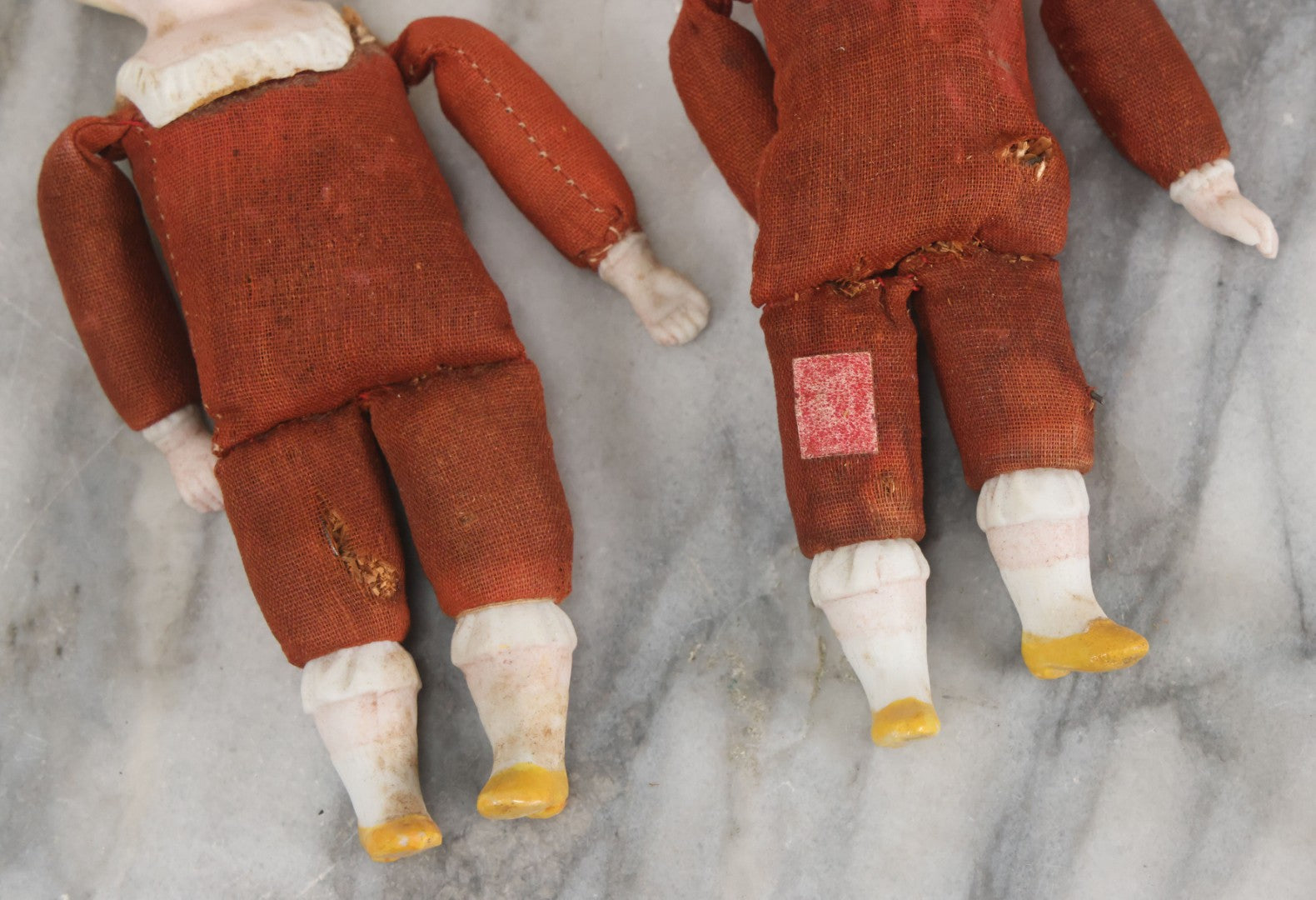 Lot 097 - Pair Of Antique Bisque Dolls With Boy And Girl With Blue Bows And Sawdust Filled Cloth Bodies, Note Girl's Head Detached, Holes In Bodies, With Sawdust Leakage, 6-1/4" Height Each