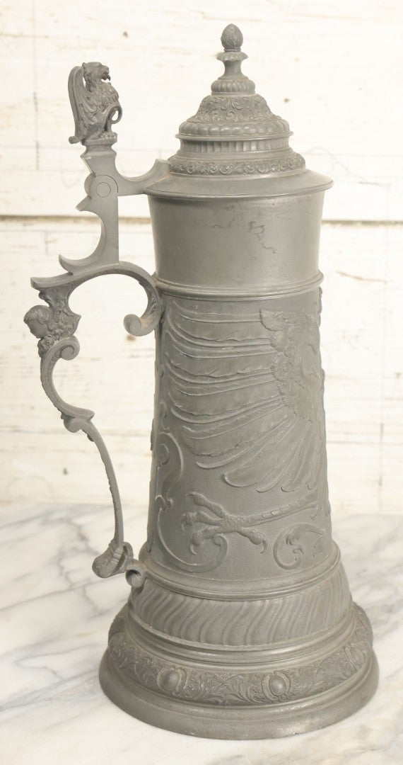 Lot 002 - Antique German Pewter Stein With Eagle, Griffin, And Cherub Motifs, Hinged Lid, Overall Height 14-1/4", Base 6-3/8" Diameter