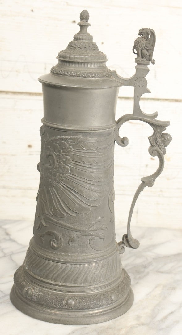 Lot 002 - Antique German Pewter Stein With Eagle, Griffin, And Cherub Motifs, Hinged Lid, Overall Height 14-1/4", Base 6-3/8" Diameter