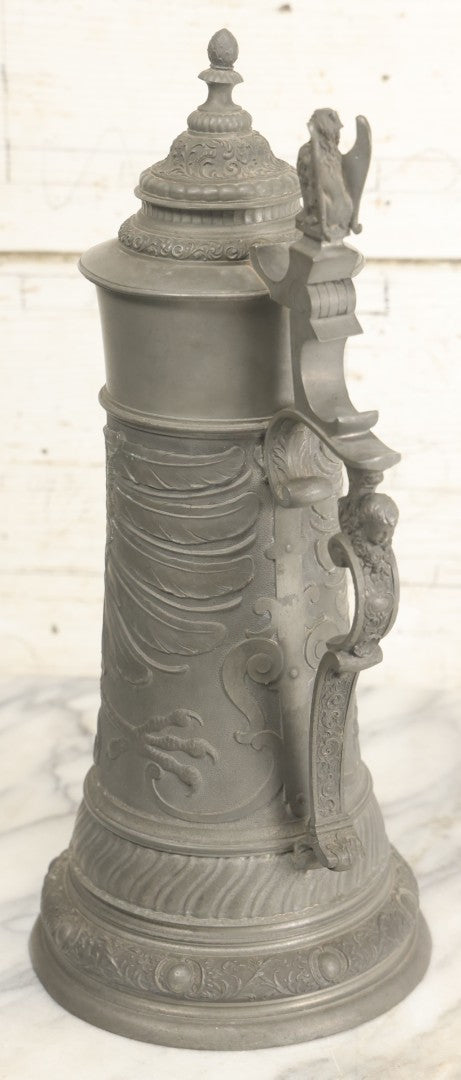 Lot 002 - Antique German Pewter Stein With Eagle, Griffin, And Cherub Motifs, Hinged Lid, Overall Height 14-1/4", Base 6-3/8" Diameter