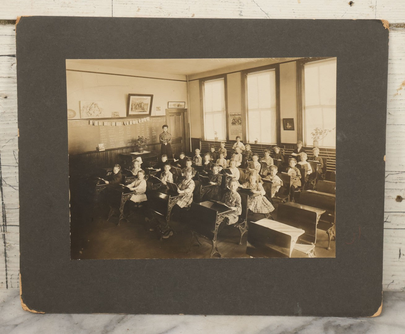 Lot 060 - Antique Boarded Photograph Of The Interior Of A 2Nd Grade Classroom With School Children, Teacher Holding Books,