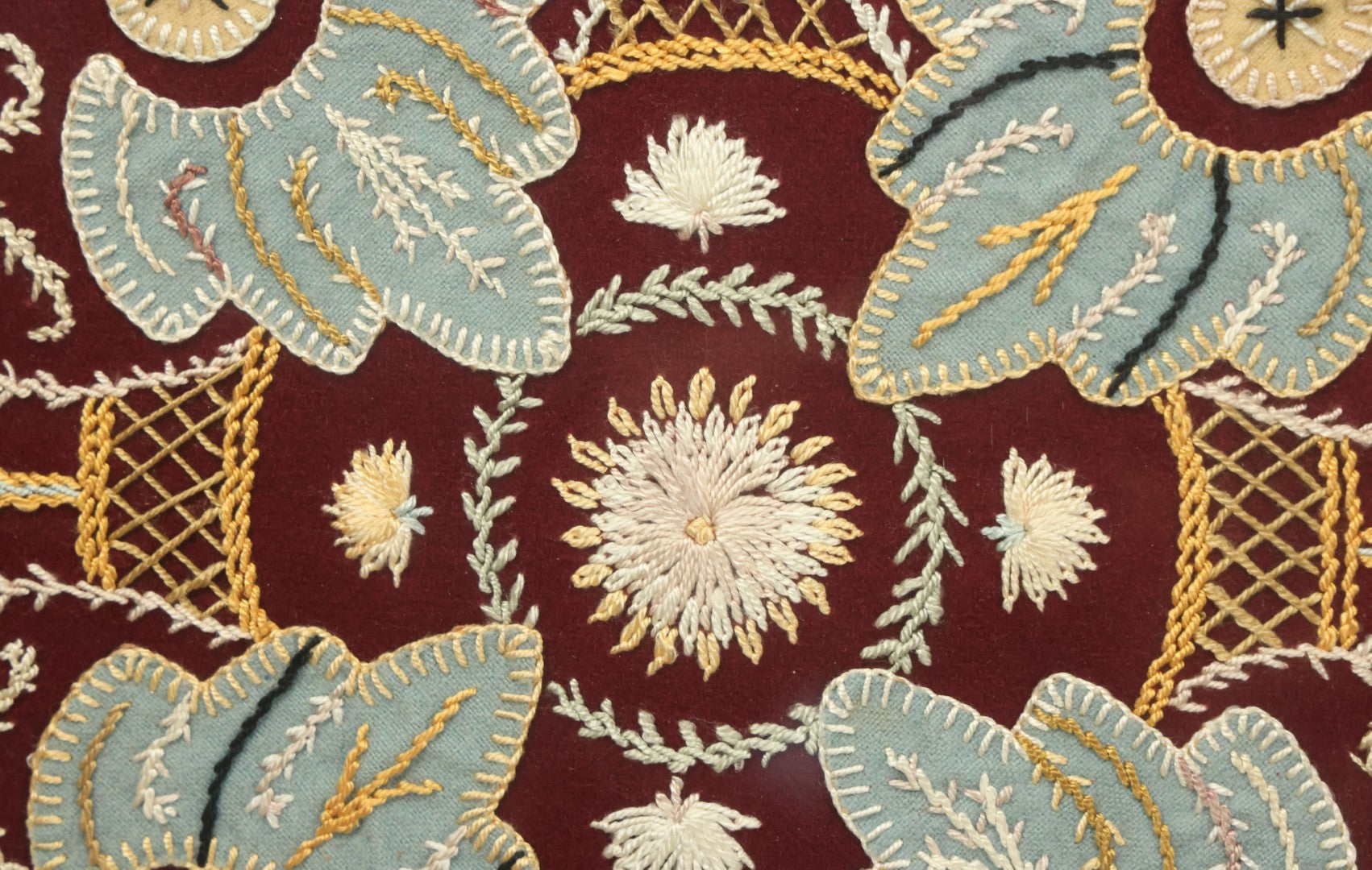 Lot 028 - Vintage Folk Art Needlepoint Embroidery Medallion With Blue, Red, And Yellow Thread On Maroon Field, In Frame