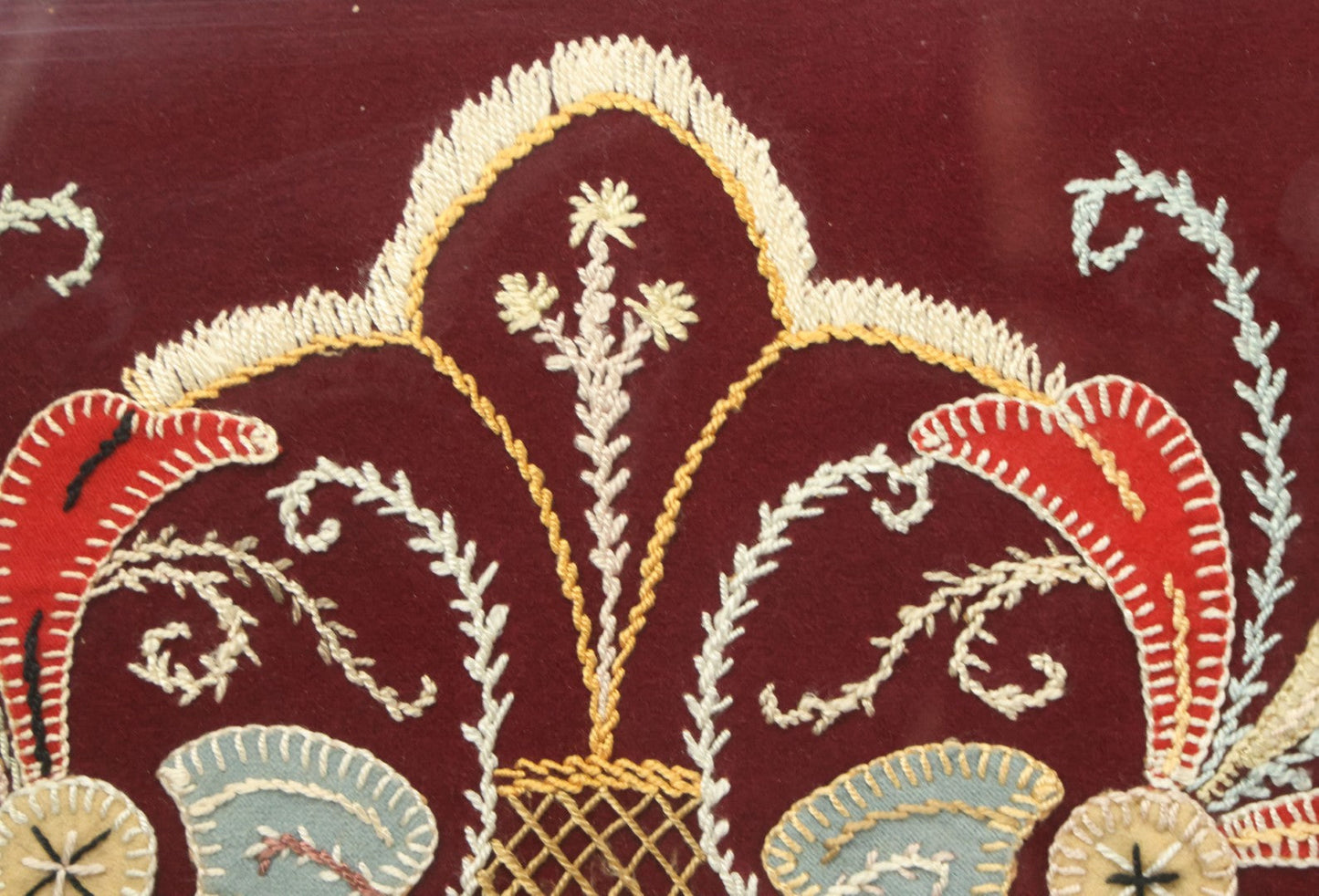 Lot 028 - Vintage Folk Art Needlepoint Embroidery Medallion With Blue, Red, And Yellow Thread On Maroon Field, In Frame