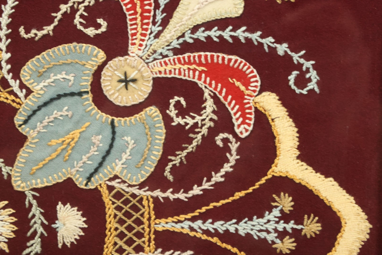 Lot 028 - Vintage Folk Art Needlepoint Embroidery Medallion With Blue, Red, And Yellow Thread On Maroon Field, In Frame