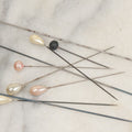 Lot 088 - Grouping Of Nine Vintage Hat Pins Including Pin With Painted Head With Purple Flowers, Mother Of Pearl Pin Heads, And More