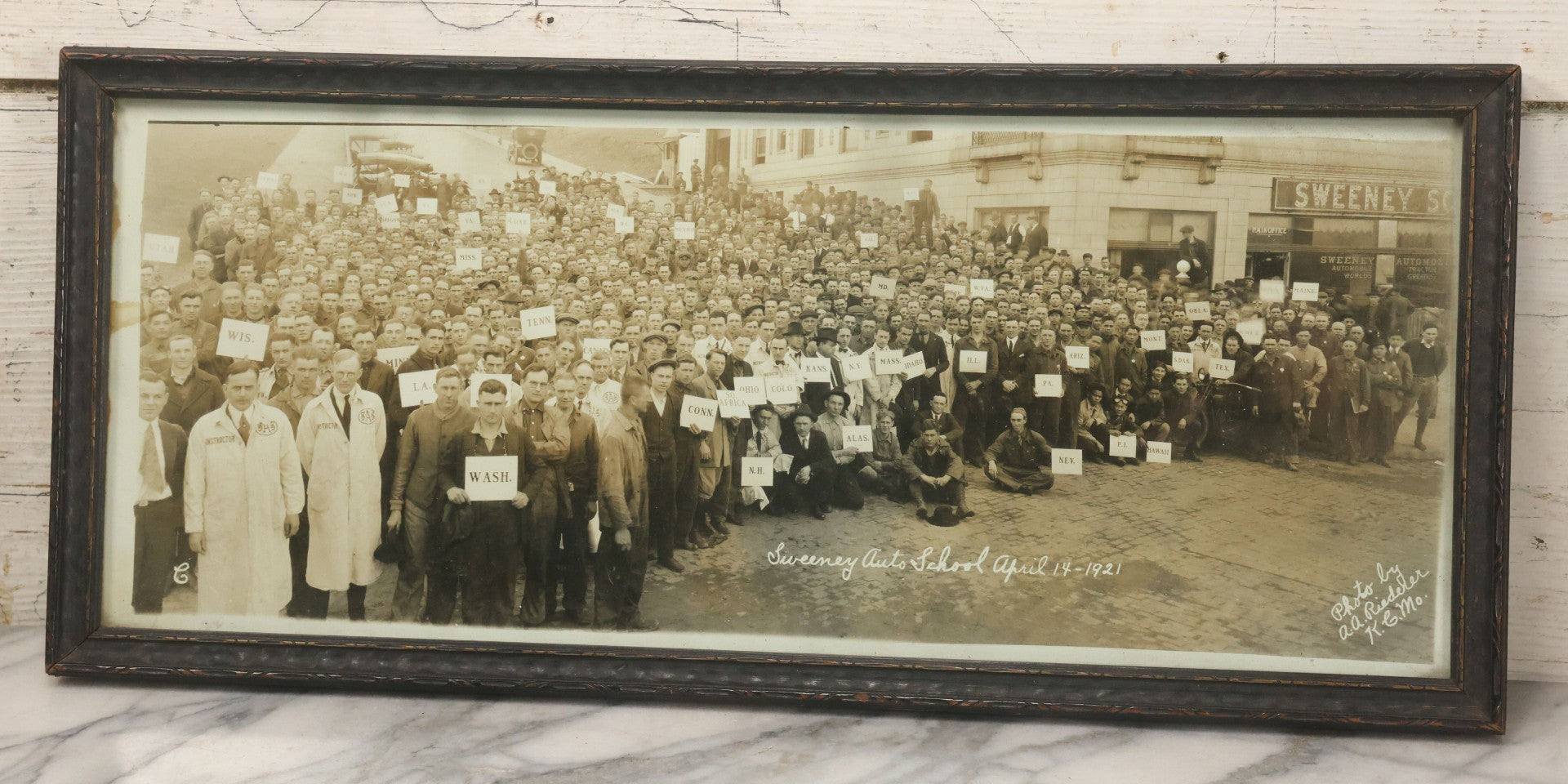 Lot 009 - Antique Framed "Yard-Long" Group Photograph Of The Students Of Sweeney Auto School, April 14th, 1921, Photo Taken By Riederer, Kansas City, Missouri, Note Texas Man On Motorcycle, 21" x 9-1/4"