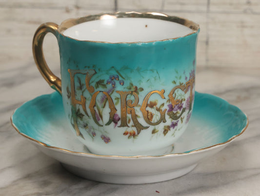Lot 064 - Antique "Forget Me Not" Porcelain Cup And Saucer With Purple Flowers, Teal Coloring, And Gold Trim, Marked Made In Germany