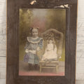 Lot 077 - Antique Boarded Tinted Photograph Of Young Girl In Blue Dress Standing Besides Wicker Chair With Her Period China Doll, Note Color Tinting Notes On Verso