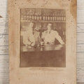 Lot 083 - Antique Boarded Occupational Photograph Of Two Bartenders Standing Behind Bar Posing With Bottles Of Elks Club Whiskey, Other Advertisements Visible Including For Boston Cadet Cigars, Note Damaged Upper Right Corner