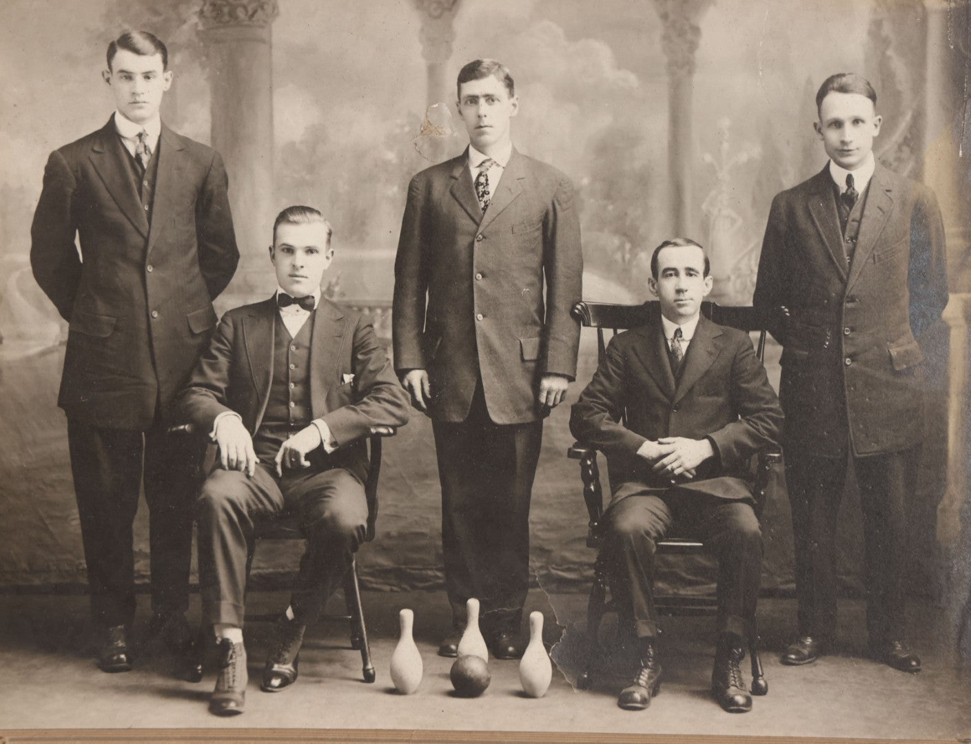 Lot 084 - Antique Boarded Photograph Of Bowling Team Of Five Men Posing With Three Bowling Pins And Bowling Ball, Note Loss To Lower Left Corner, Hole To Left Of Center Mans Head