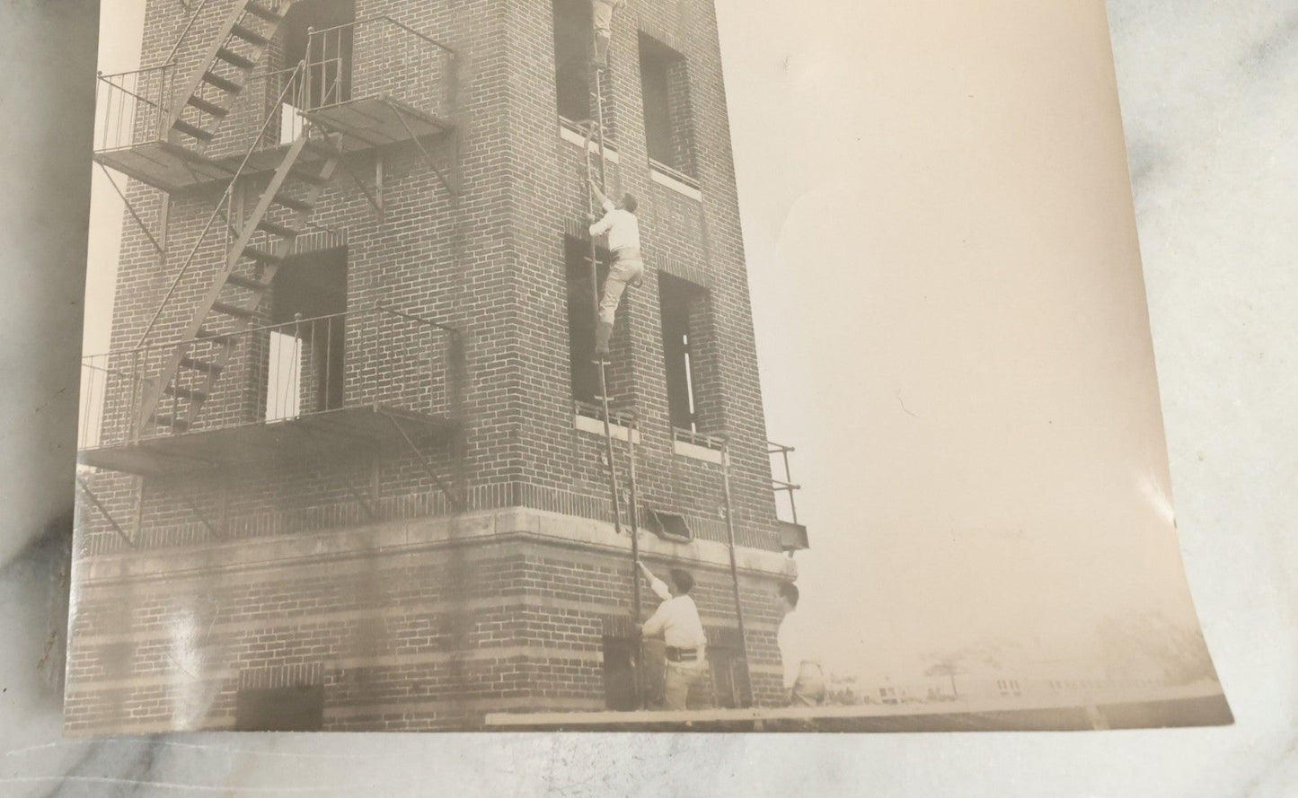 Lot 113 - Vintage Large Format Glossy Photograph Of Men Climbing Ladder On Brick Tower, Likely Firefighter Training Related