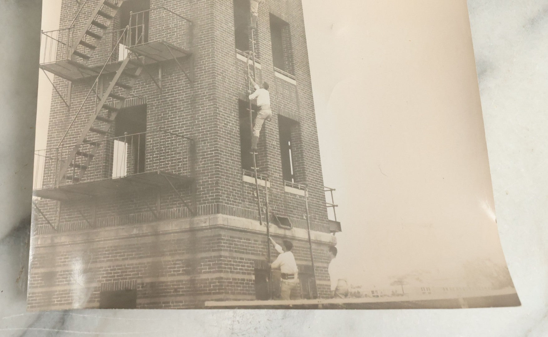 Lot 113 - Vintage Large Format Glossy Photograph Of Men Climbing Ladder On Brick Tower, Likely Firefighter Training Related