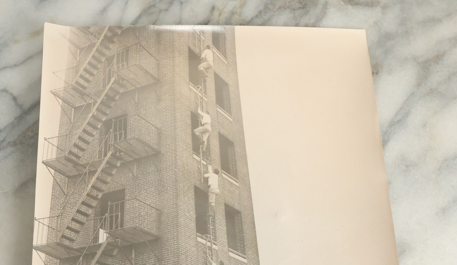 Lot 113 - Vintage Large Format Glossy Photograph Of Men Climbing Ladder On Brick Tower, Likely Firefighter Training Related