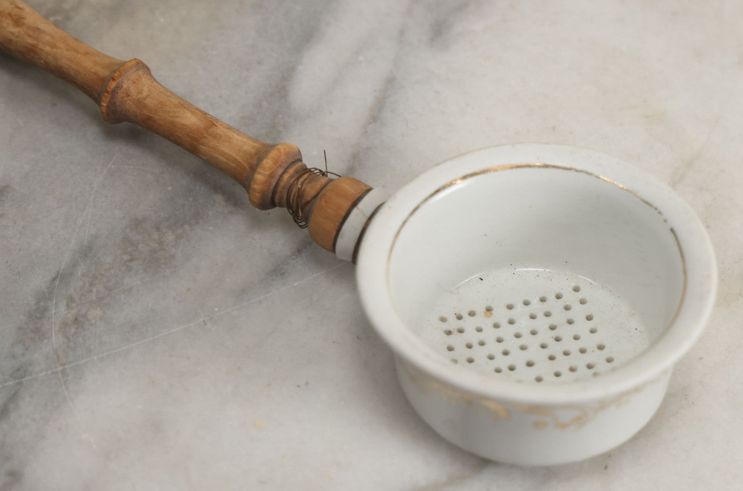 Lot 132 - Vintage Porcelain Tea Strainer With Gold Painted Details And Wire Attached Wooden Handle, Note Repairs