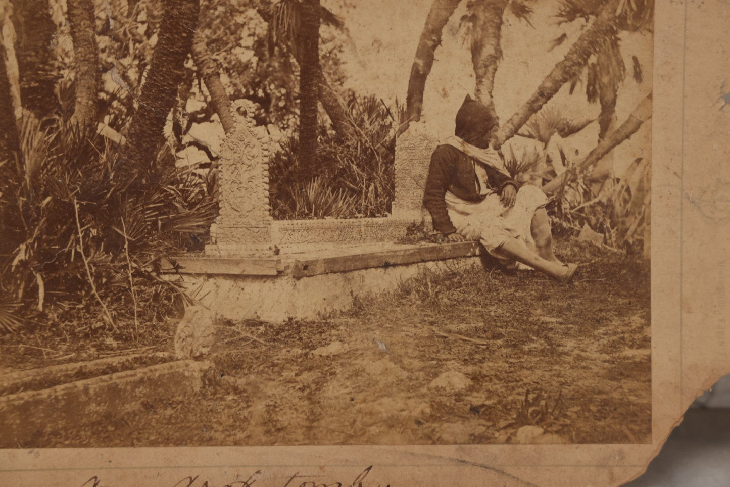 Lot 100 - Antique Boarded Photograph Of Person Sitting At Gravesite Identified As "An Arab Tomb", Partial Photographer Mark And Monogram On Photo Board, Out Of Algeria, Note Losses And Cracking Throughout Photo And Board, Poor Condition