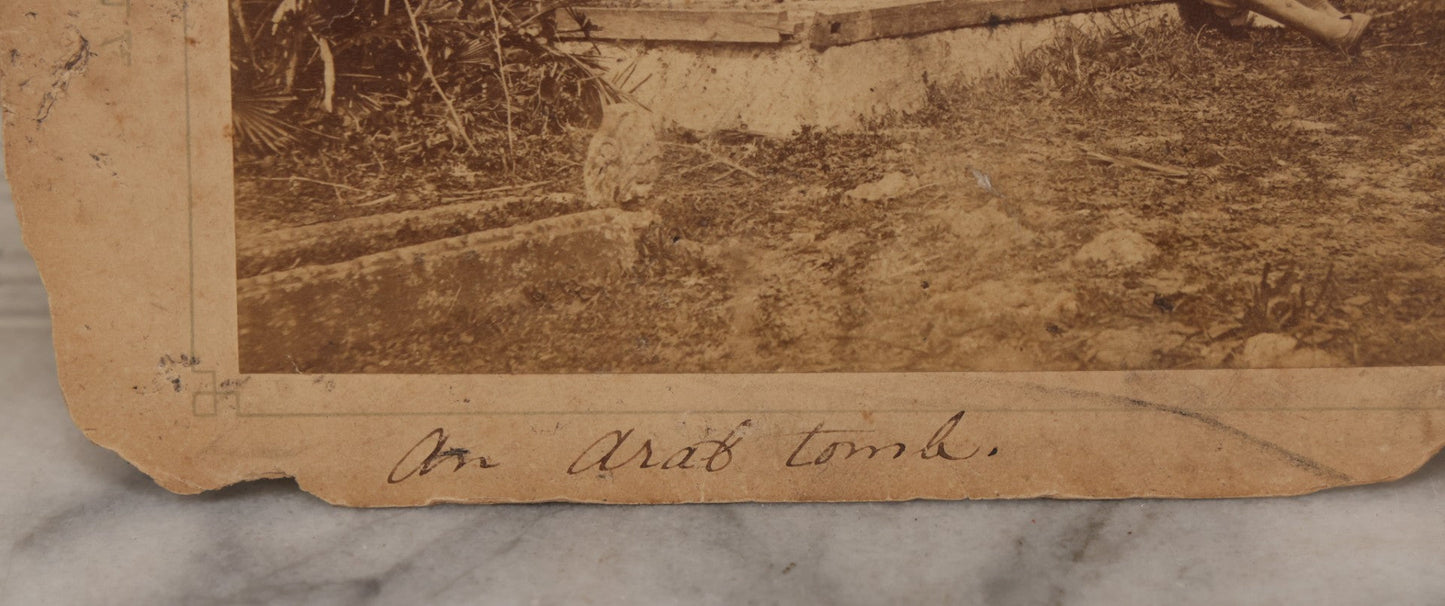 Lot 100 - Antique Boarded Photograph Of Person Sitting At Gravesite Identified As "An Arab Tomb", Partial Photographer Mark And Monogram On Photo Board, Out Of Algeria, Note Losses And Cracking Throughout Photo And Board, Poor Condition