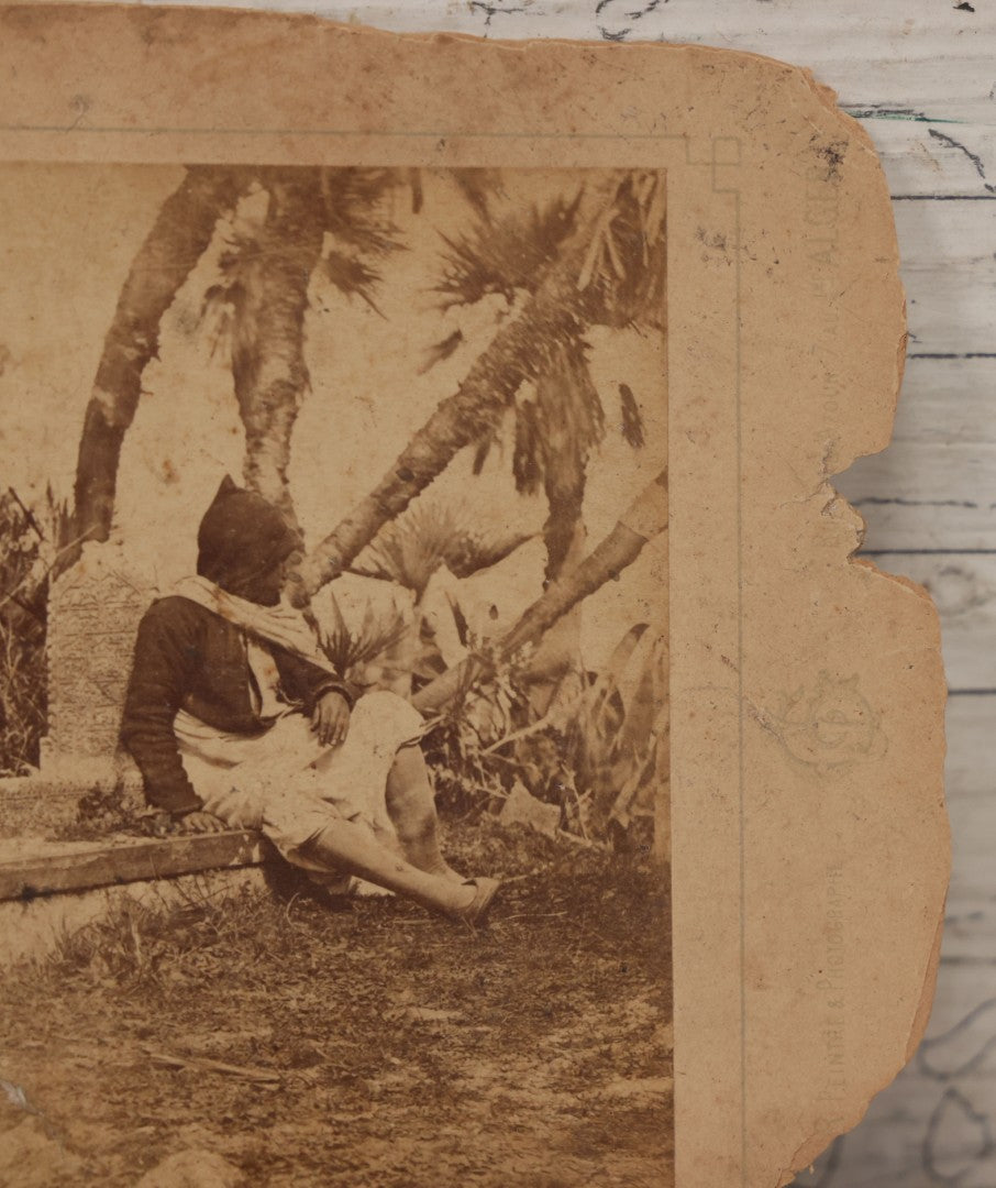 Lot 100 - Antique Boarded Photograph Of Person Sitting At Gravesite Identified As "An Arab Tomb", Partial Photographer Mark And Monogram On Photo Board, Out Of Algeria, Note Losses And Cracking Throughout Photo And Board, Poor Condition