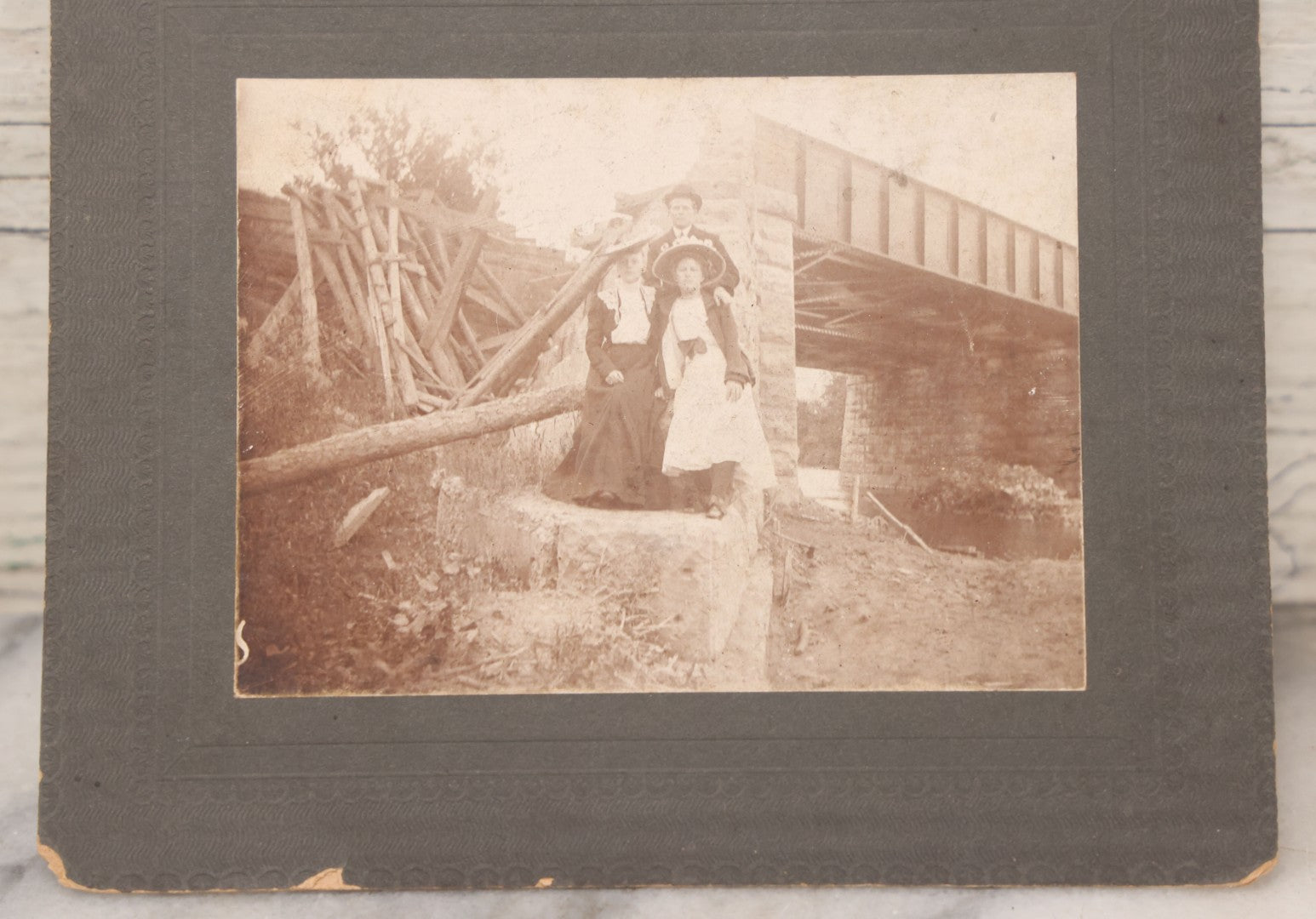 Lot 109 - Antique Boarded Photograph Of Two Women And Man Posing Beside Partially Collapsed Railroad Bridge