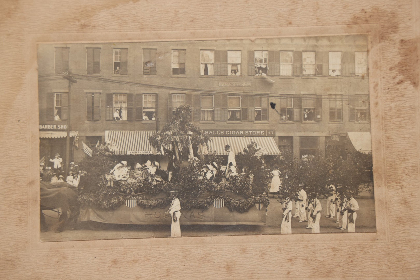 Lot 114 - Antique Boarded Photograph Of Patriotic Parade With Swedish Float With "Hoganas" Banner, Sign On Building "Bangs Block" (Likely Springfield, Mass.), Other Signs "Ball's Cigar Store", "Ladies & Gents Lounge", Barber Shop And "Sam Sing Laundry"