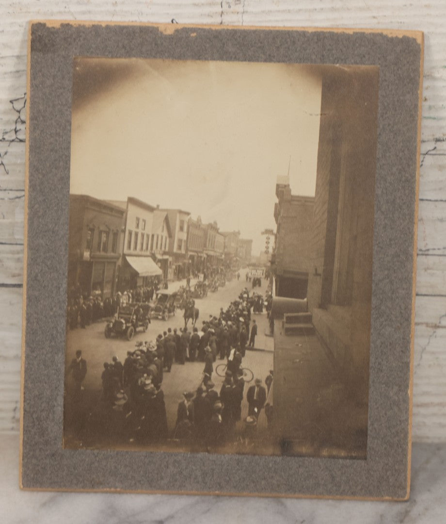Lot 115 - Pair Of Antique Boarded Photographs Of Parade And Onlookers With Early Automobiles And People On Horseback Signs For "Red Front Store" And "National Bank"