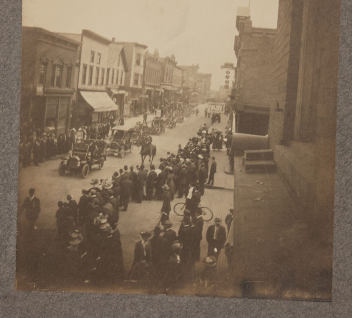 Lot 115 - Pair Of Antique Boarded Photographs Of Parade And Onlookers With Early Automobiles And People On Horseback Signs For "Red Front Store" And "National Bank"