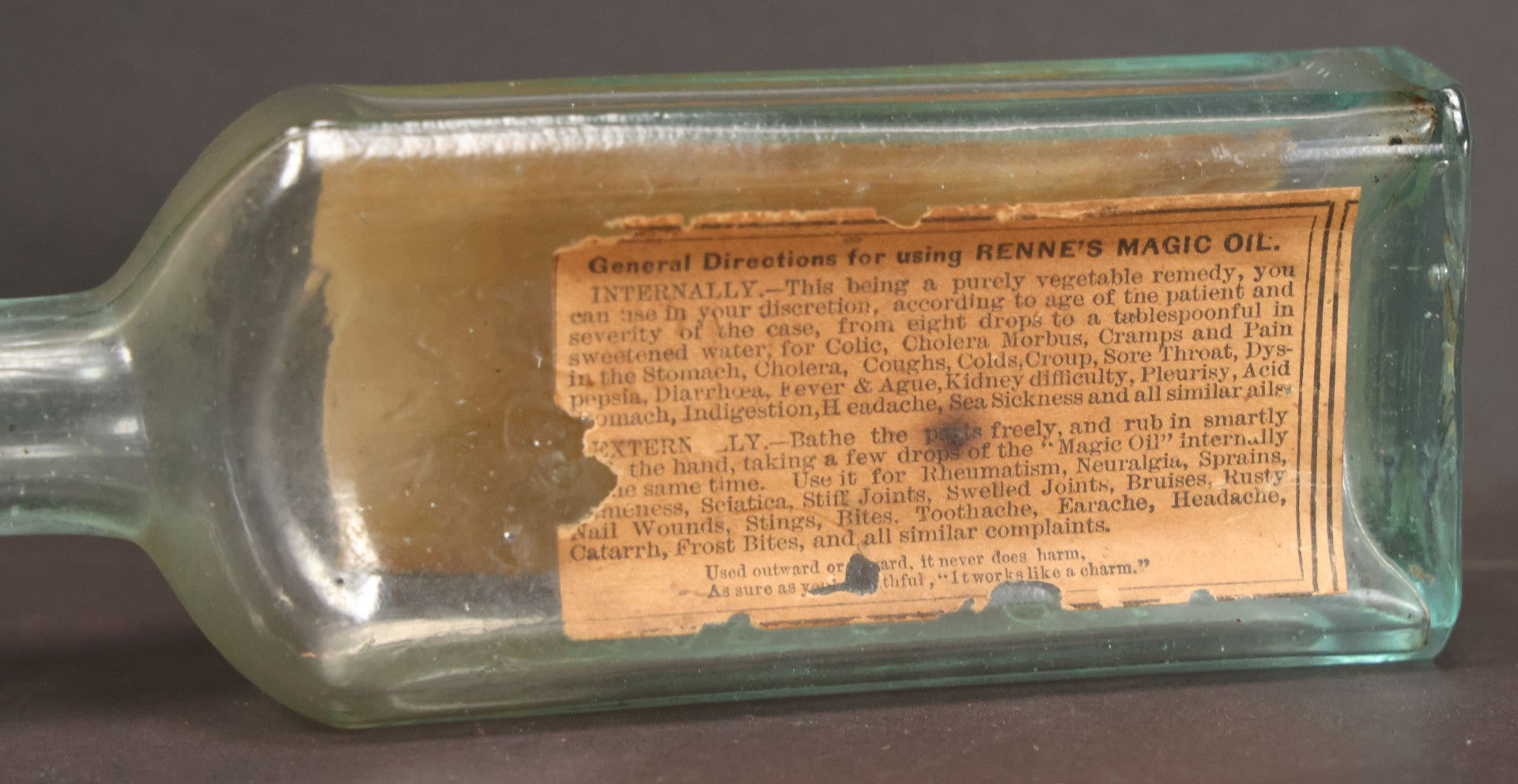 Lot 013 - Antique Bottle With Embossed Text And Original Paper Labels For Renne's Pain Killing Magic Oil Patent Medicine, "It Works Like A Charm; Clean Safe And Delicious" Manufactured By T.W. Warner & Co., New York, 6" Height