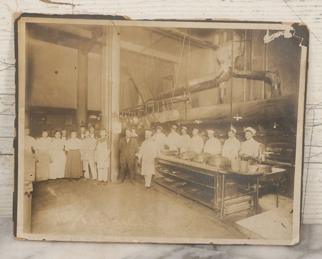 Lot 124 - Antique Boarded Occupational Photograph Of Kitchen Staff At Their Stations In Large Industrial Kitchen With Period Uniforms And Cooking Appliances Visible