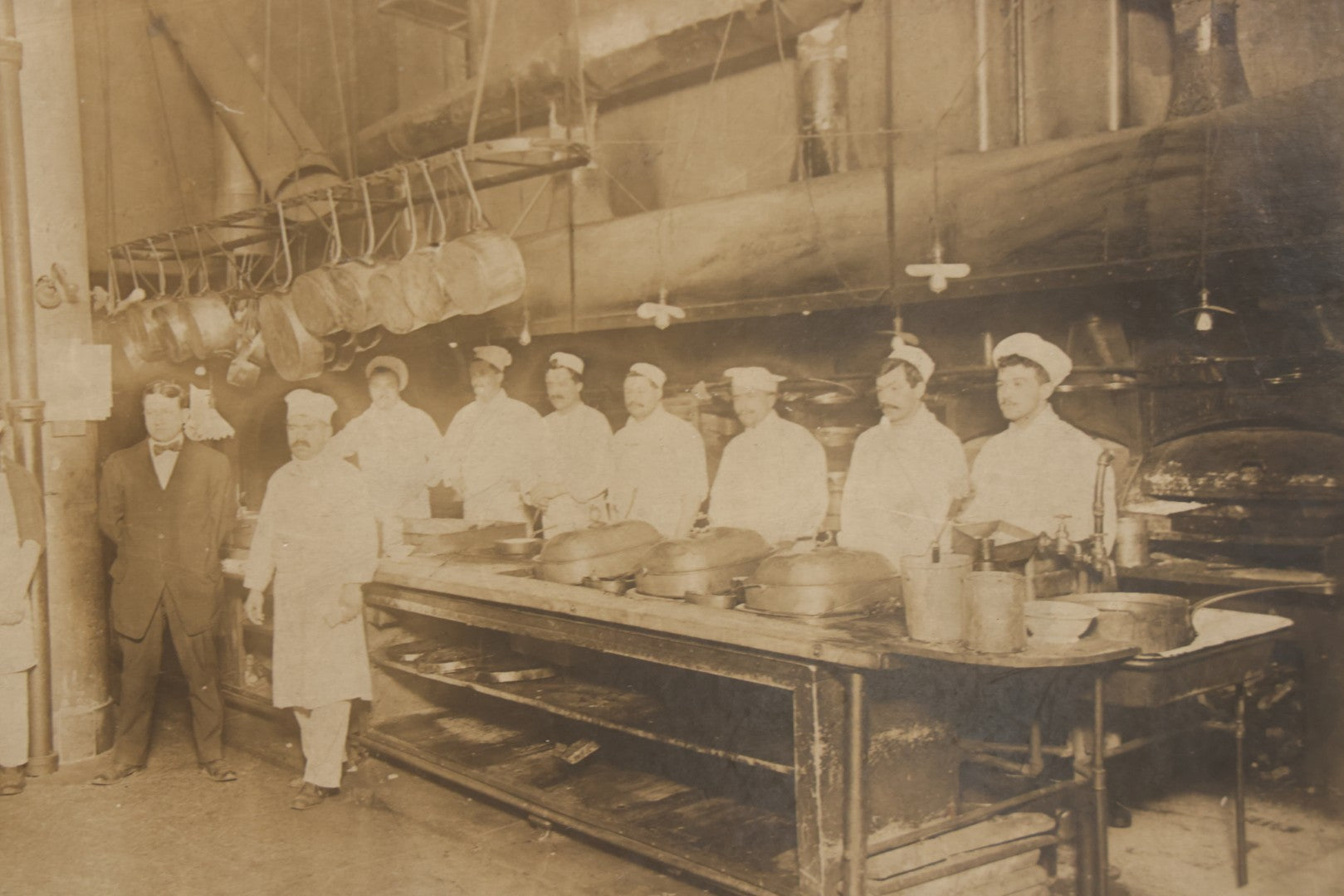Lot 124 - Antique Boarded Occupational Photograph Of Kitchen Staff At Their Stations In Large Industrial Kitchen With Period Uniforms And Cooking Appliances Visible