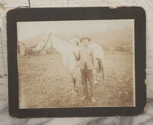 Lot 128 - Antique Boarded Photograph Of An Elderly Cowboy Smoking A Pipe Beside His White Horse
